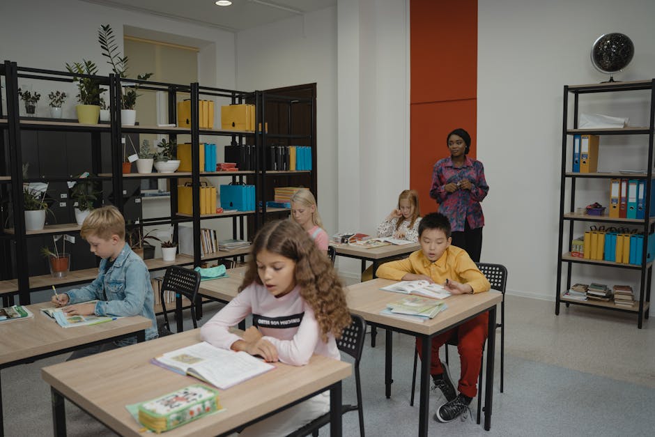 Elementary students focus on classwork with a teacher overseeing in a bright classroom.